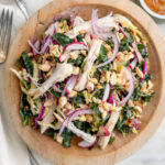 Overhead shot of Kale Peanut Salad with Chicken in a wooden bowl and fork